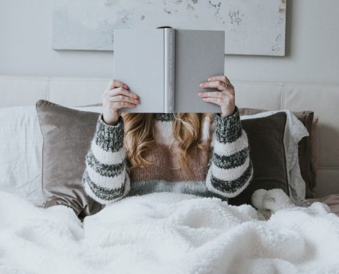 perempuan membaca buku di tempat tidur