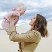 Peran Orang Tua sebagai Sumber Rasa Aman bagi Anak; gambar perempuan menggendong bayinya di udara